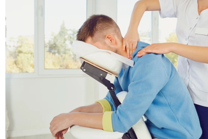 Massothérapeute offrant un massage thérapeutique aux épaules et au cou d'une cliente dans un contexte professionnel